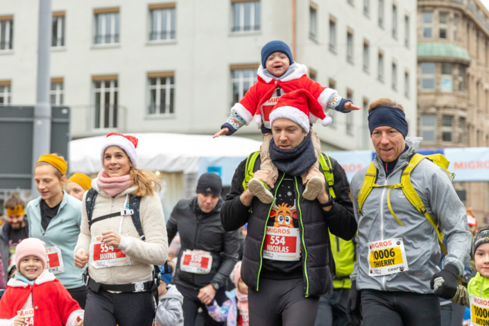 Eine Gruppe von Menschen mit Weihnachtsmützen rennt durch eine Stadt.