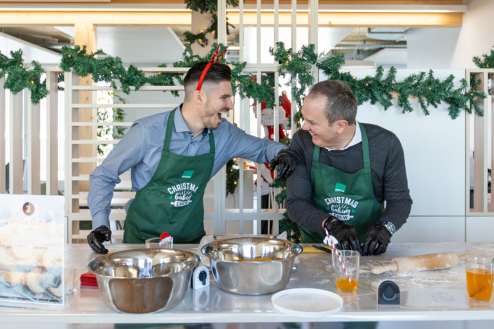 Zwei Männer in grünen Schürzen bereiten Essen zu.