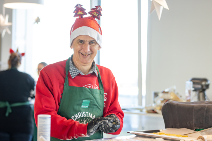 Ein Mann mit Weihnachtsmütze und Schürze.