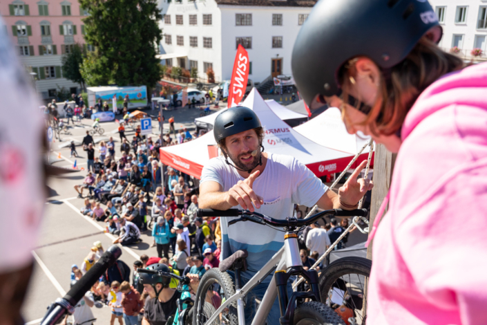 A man rides a bicycle in front of a crowd of people.