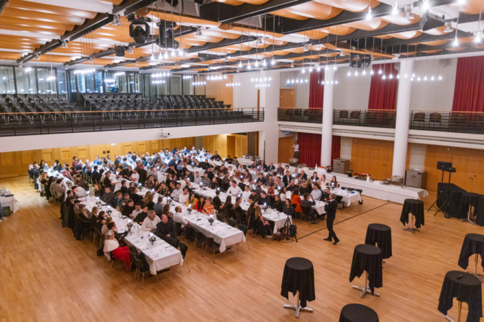 Ein großer Saal mit vielen Leuten, die an Tischen sitzen.