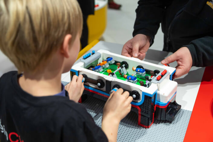 Ein kleiner Junge spielt mit einem Lego-Tisch.