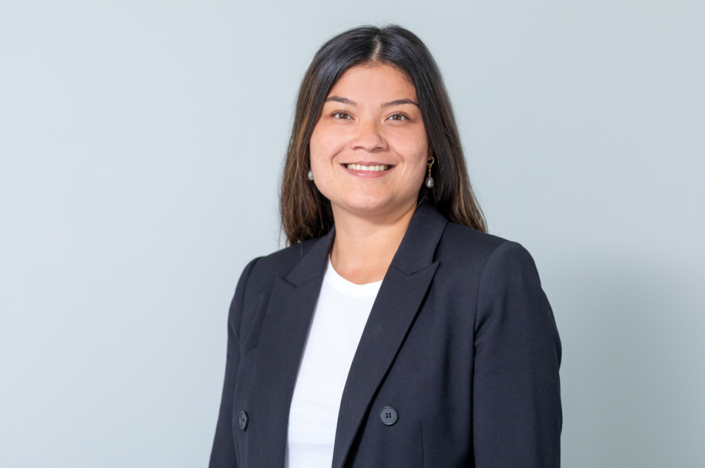 A woman in a black blazer smiles at the camera.