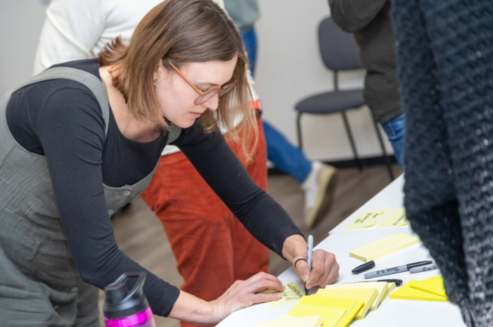 A woman writes on a table with sticky notes.