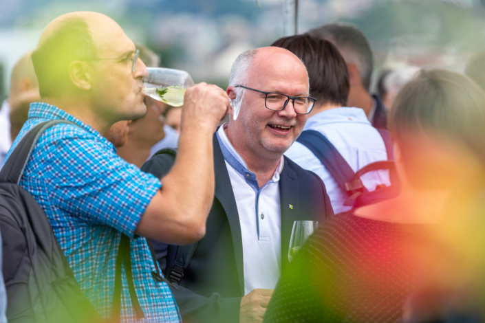 A group of people drink wine at an outdoor event.