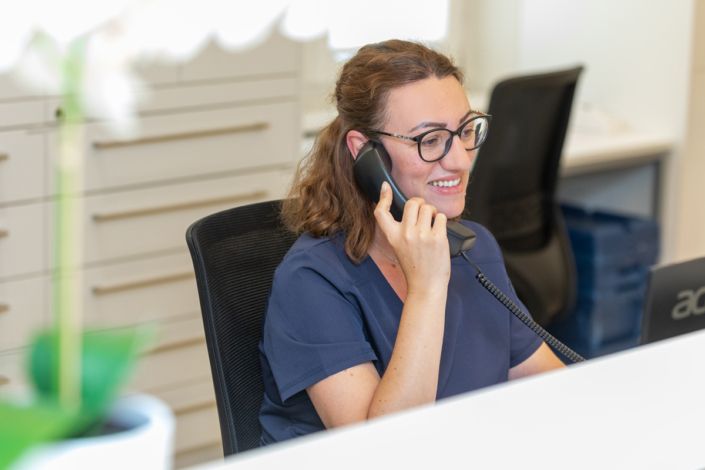 A woman sits at her desk and talks on the phone.