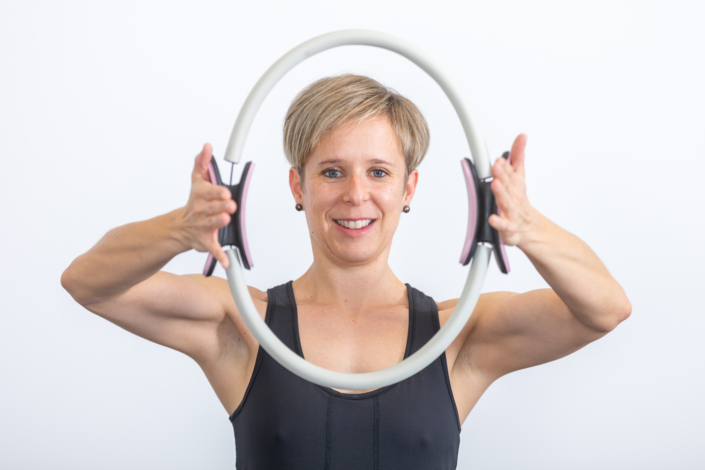 A woman holds a tire in front of a white background.