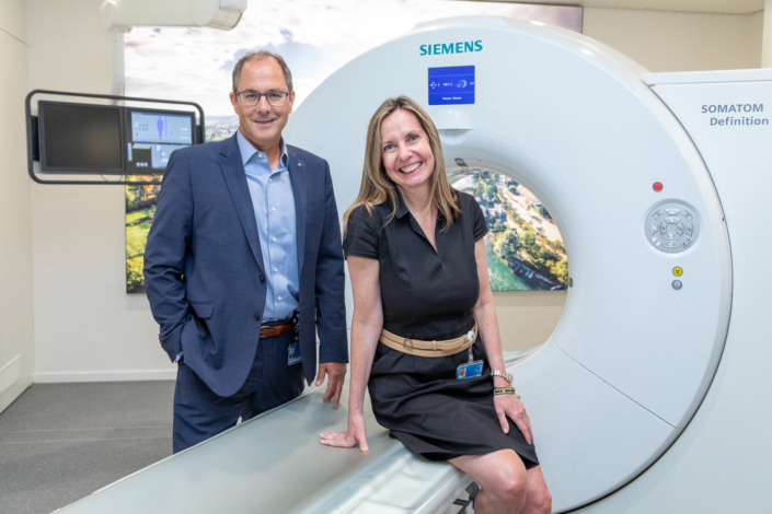 Two people pose next to an MRI machine.