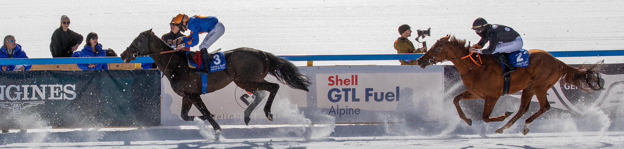 Zwei Jockeys auf Pferden rennen im Schnee.